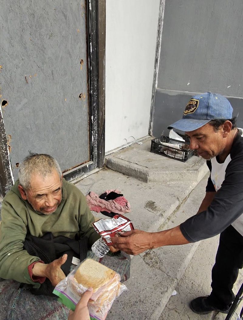 A community member holding a food package and water bottle during an outreach visit